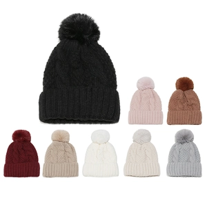 Detail of cable-knit winter beanies with soft pom-poms shown in multiple colors
