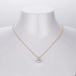Close-up of elegant round pearl pendant with sparkling diamonds on a fine gold chain