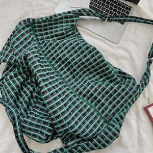 Macro shot of green and black plaid fabric texture and zipper closure on the tote bag