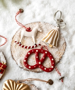 Flat lay of Nordic Christmas metal ornaments with snowman and bell on a snowy background