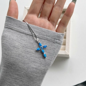 Detailed close-up of a silver cross necklace with blue teardrop-shaped opal stones