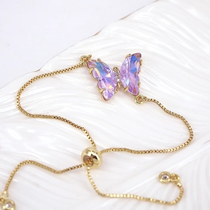 Detail of gold box chain bracelet with adjustable bead and purple rhinestone butterfly