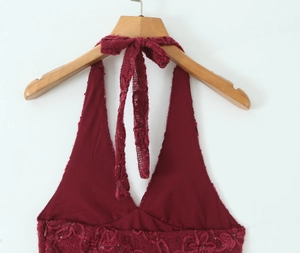 Detailed close-up of wine red lace fabric with sequins and halter neck tie design