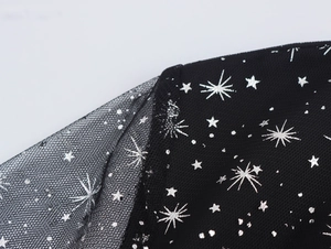 Dettaglio macro del tessuto a rete nero con paillettes a stella d'argento scintillanti