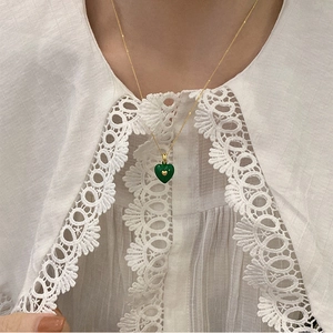Detailed macro view of a green heart pendant with gold accent on a dainty chain
