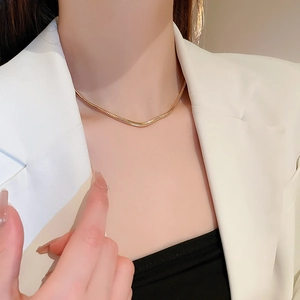 Minimalistische Schlangenknochen-Halskette in Gold getragen zum Business-Outfit
