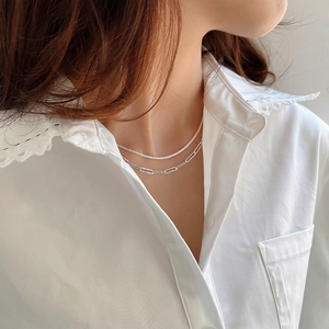 Close-up of layered 925 sterling silver chain necklace worn with white lace collar