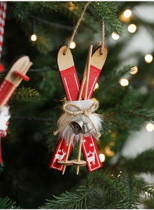 Detail of red wooden sleigh ornament with white reindeer print and silver bells on tree