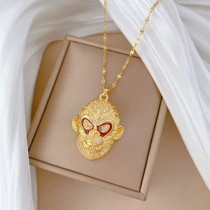 Detail of gold monkey pendant with red enamel eyes and crystals on beige silk