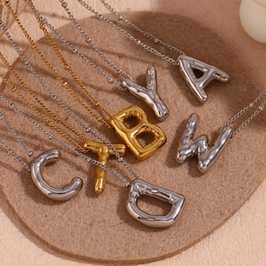 Macro-opname van 18K gouden ballonletterhangers met spiegelende afwerking op zachte mat