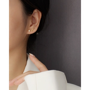 Close-up of a model wearing three golden diamond-studded star earrings on the earlobe