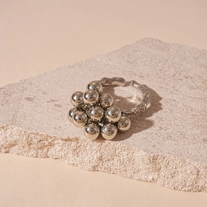 Detail of silver irregular multi-ball cluster open ring on light stone background