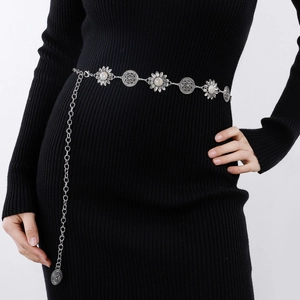Detail of silver vintage waist chain with sunflower and coin charms on a black dress