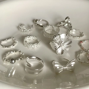 Elegant 925 sterling silver ring set with pearls and floral bow designs on a white tray