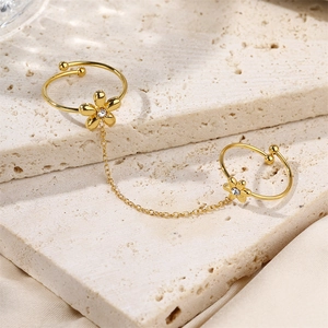 Gold double finger ring with crystal flowers and chain link on a stone display