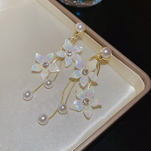 Detail of floral earrings with shimmering pearls, sparkling rhinestones and gold tassels