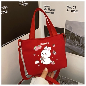 Detail of red canvas crossbody bag featuring a cute rabbit print and adjustable strap