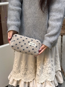 Close-up of soft beige plush pencil case featuring blue floral patterns and brand label