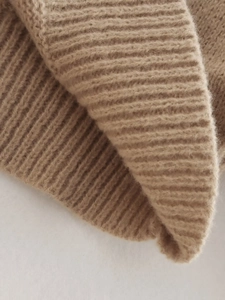 Macro detail of the beige rib-knit sweater showing soft texture and premium weave pattern