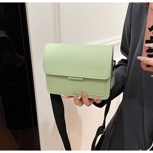 Close-up of mint green PU leather crossbody bag with a wide black textile strap