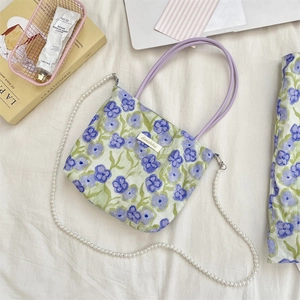 Dettaglio borsa in tela floreale con motivo viola e tracolla di perle eleganti
