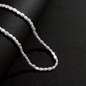Baroque freshwater pearl necklace with rice-shaped white pearls on black leather background