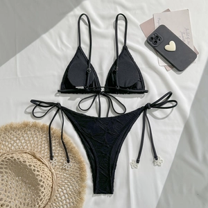 Detail of textured black bikini fabric with pearl flower accents on side ties