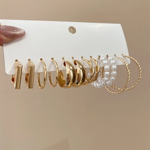 Detail of 6 pairs golden earring set featuring pearls, hoops and geometric metal dangles