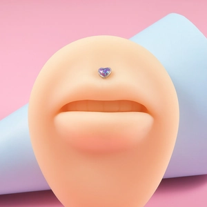 Macro shot of heart-shaped purple opal labret stud on a silicone lip model piercing