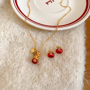 Close-up of gold-plated lucky bag jewelry set with red zircon details on soft white fabric
