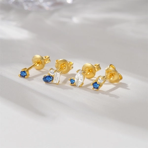 Macro view of gold-plated S925 silver stud earrings with blue and white zircon gemstones