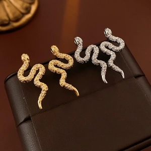 Vue macro de boucles d'oreilles serpent en or et argent avec zircons et yeux verts