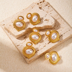 Vintage gold plated flower pearl stud earrings displayed on a beige stone surface