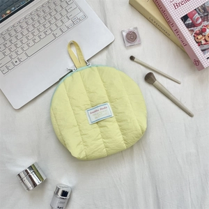Detail of round quilted shell cosmetic bag with mint green zipper and top handle