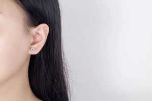 Close-up of elegant silver ball cubic zirconia stud earrings worn on the earlobe