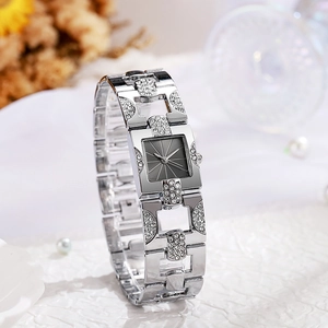 Detail of silver square quartz watch with rhinestones on textured fabric and dried flowers