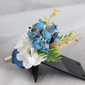 Wedding boutonniere with blue berries and white flowers on a black display stand