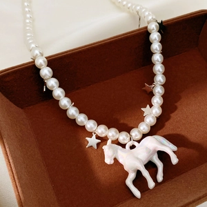 Detailed shot of pearlescent pony charm and silver star pendants on beaded pearl necklace