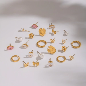 Set of minimalist gold earrings with pearls, zircons, flowers, and bows on white background