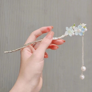 Detail of silver hair stick with blue magnolia flowers and elegant pearl tassels