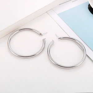 Close-up of polished silver stainless steel hoop earrings on a magazine background