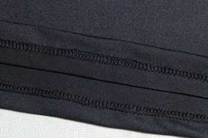 Macro shot of double-needle stitching on the hem of a black long-sleeve dress