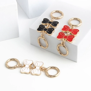 Golden bowknot extension chain charms in black, red, and white for crossbody bags