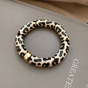 Detail of leopard print tubular beads and a golden polished metal ball on a stylish bracelet