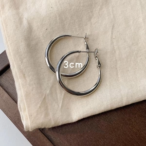 Detailed top view of silver 3cm chunky hoop earrings on natural linen background