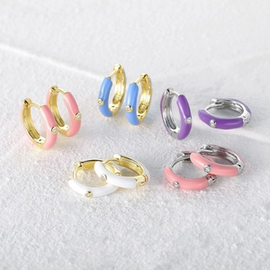 Macro detail of five colorful enamel huggie earrings with gold and silver accents