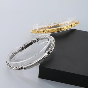 Detail of gold and silver stainless steel dragon bone bracelets with Greek fret patterns