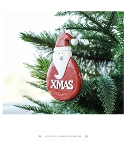 Detail of red Santa Claus teardrop ornament with XMAS text hanging on a Christmas tree