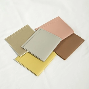 Detailed view of stacked colorful PU leather drawstring storage pouches on white fabric