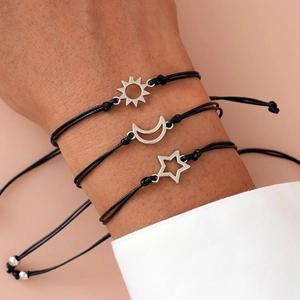 Close-up of three woven friendship bracelets with sun, moon, and star charms